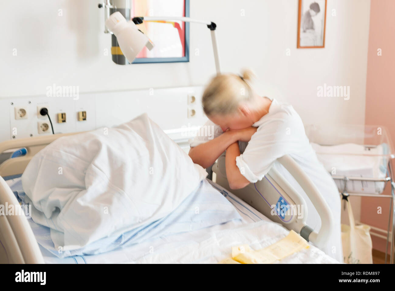 Mid adult woman leaning against hospital bed Stock Photo