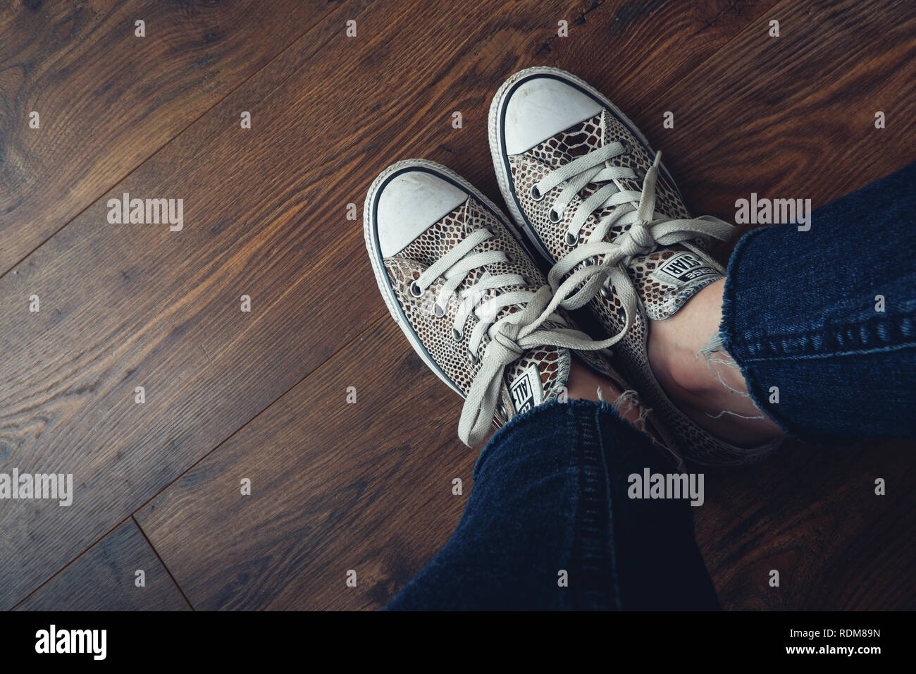 Converse all star shoes / trainers with an animal print, photographed  against wooden floor Stock Photo - Alamy
