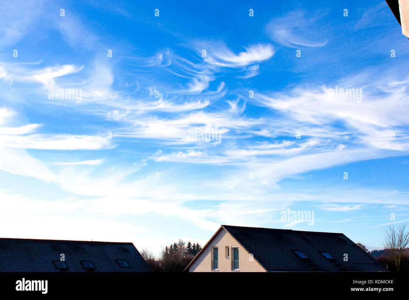 blue sky background with clouds in front of houses Stock Photo - Alamy