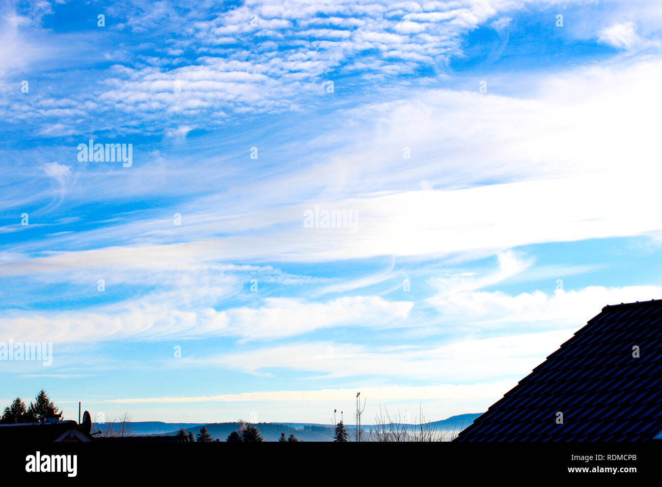 blue sky background with clouds in front of houses Stock Photo - Alamy