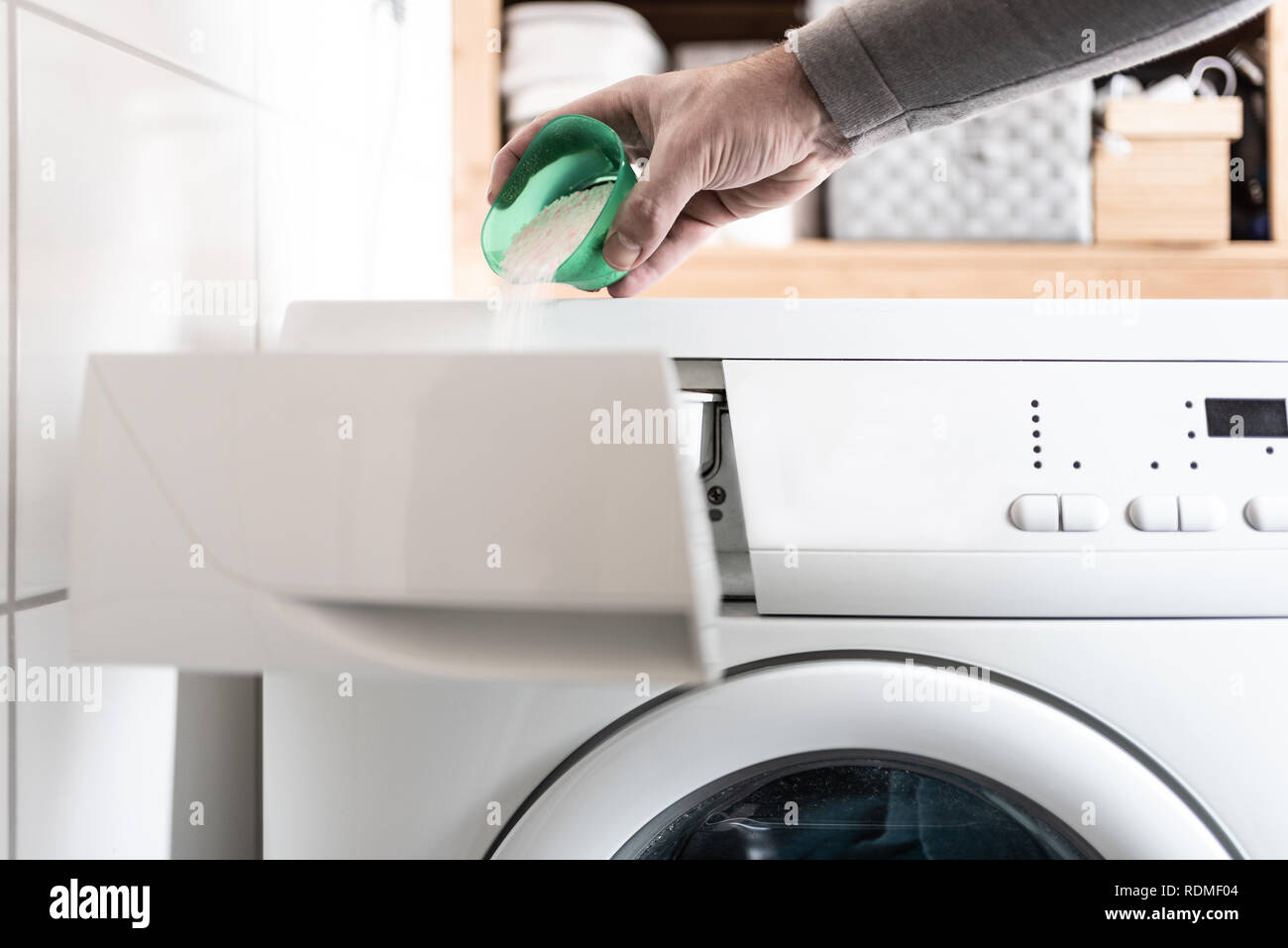 person using dosing aid to pout laundry detergent powder into washing machine Stock Photo
