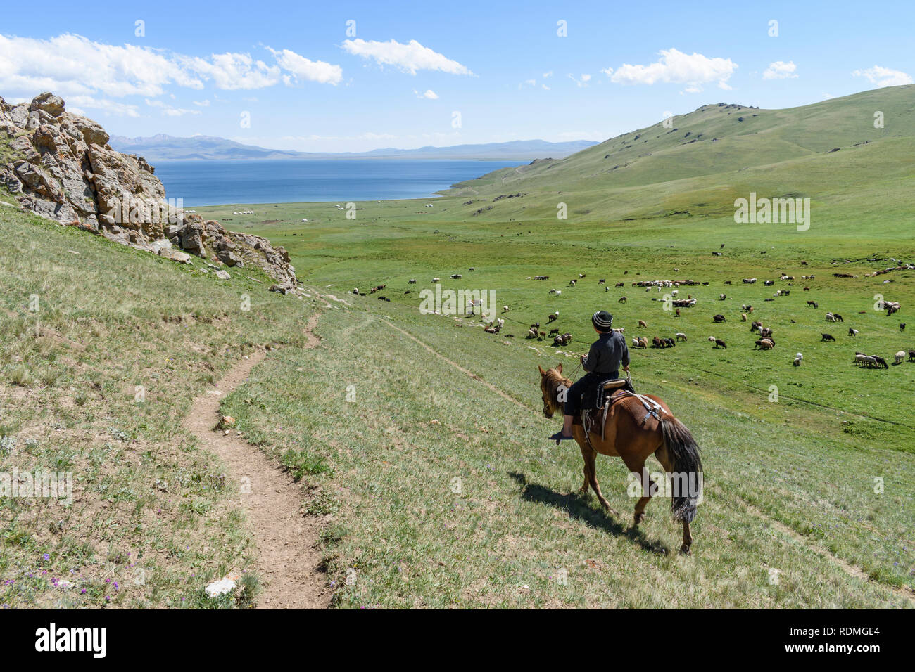 man on horseback riding through valley with lake in the distance, Song kul,  Kyrgyzstan Stock Photo - Alamy