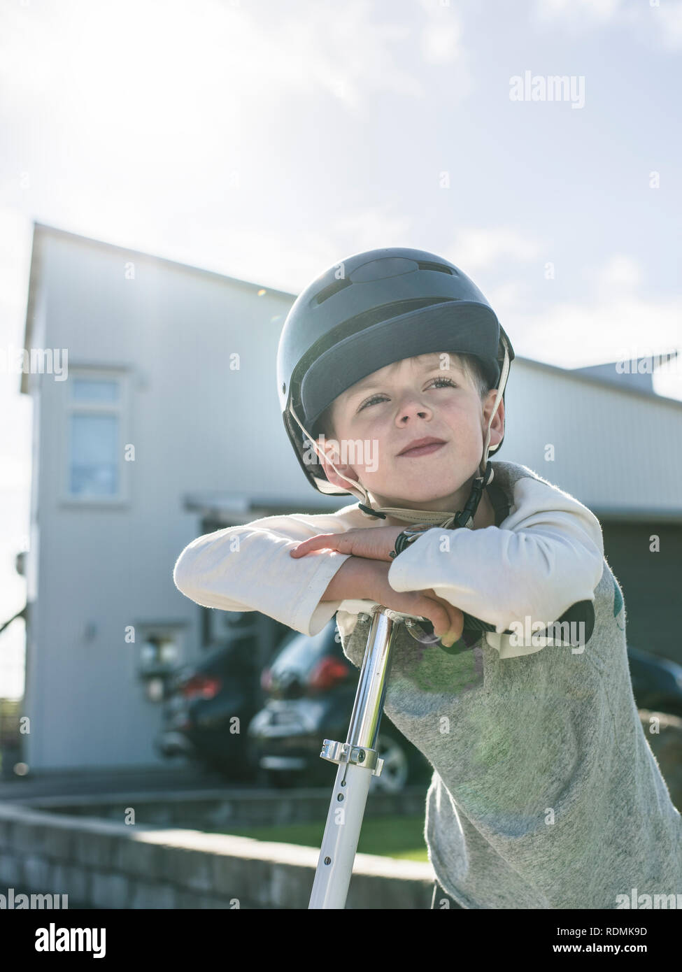 Boy in bicycle helmet standing with kick scooter Stock Photo Alamy