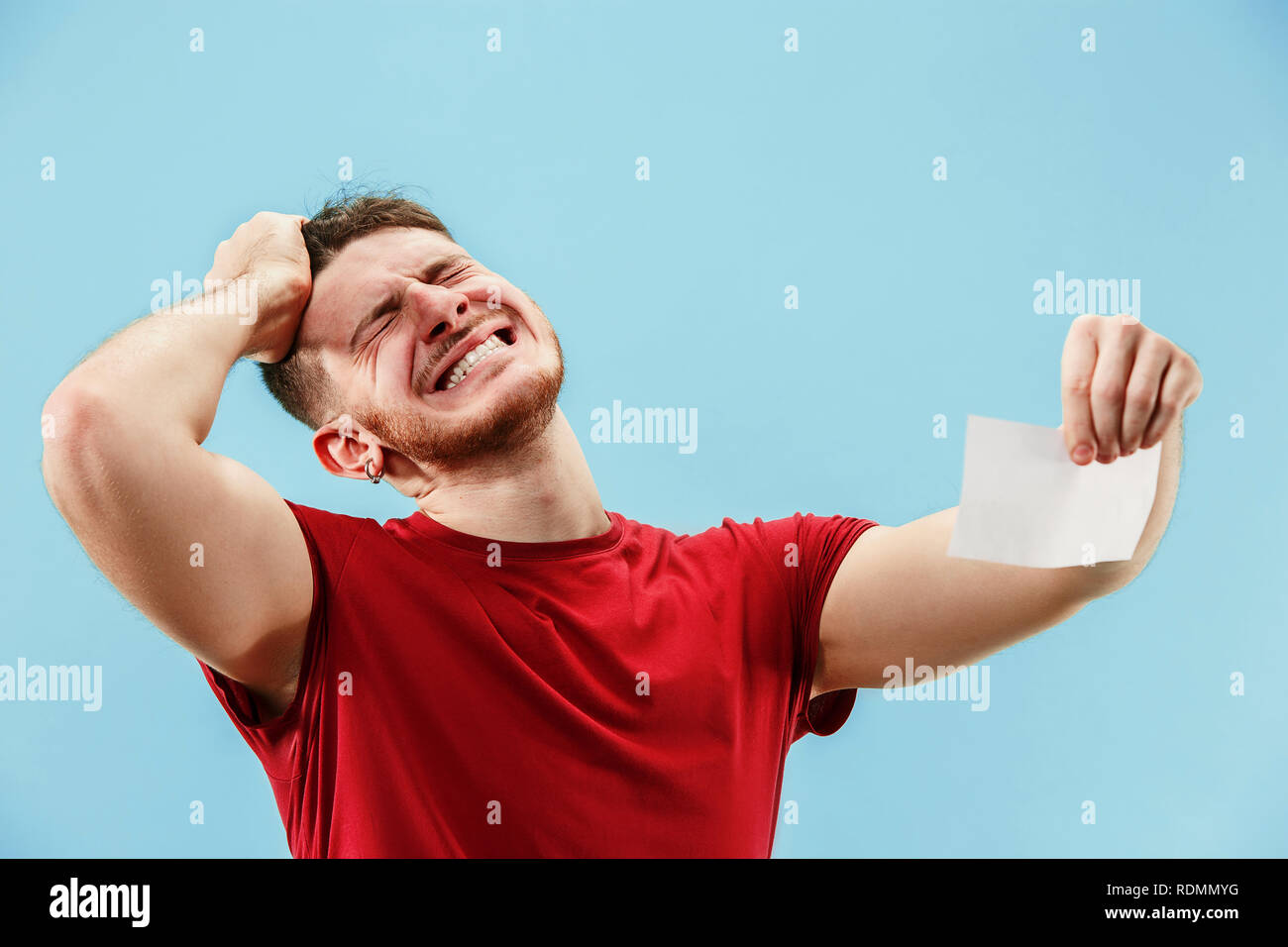 Young boy with a surprised unhappy failure expression bet slip on blue ...