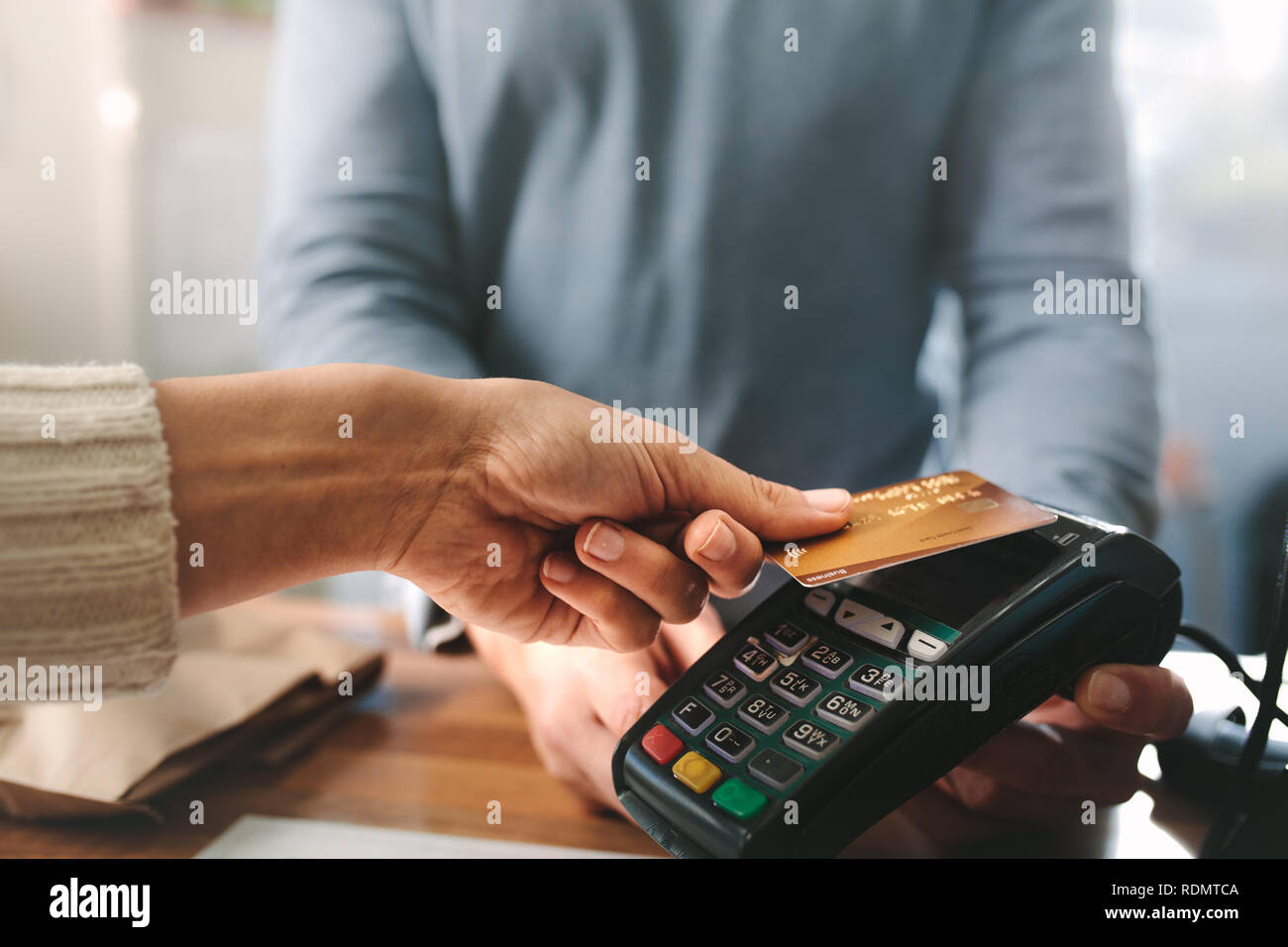 Pharmacist accepting credit card by contactless payment.  Woman purchasing products in the pharmacy. Pharmacist hands charging with credit card reader Stock Photo