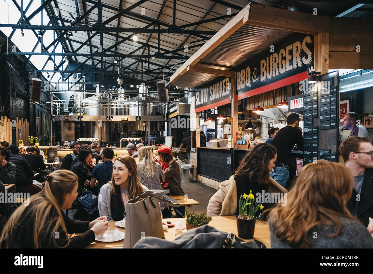 London, UK - January 13, 2019: People by BBQ and burger stand in Mercato Metropolitano, the first sustainable community market in London focused on re Stock Photo