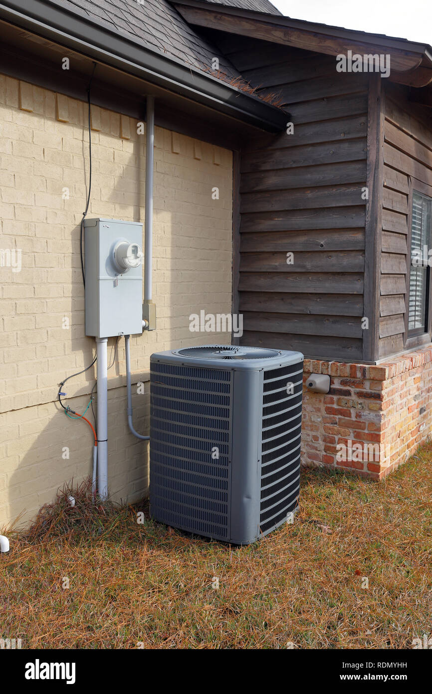 Gray Air Conditioner condenser compressor unit next to painted brick