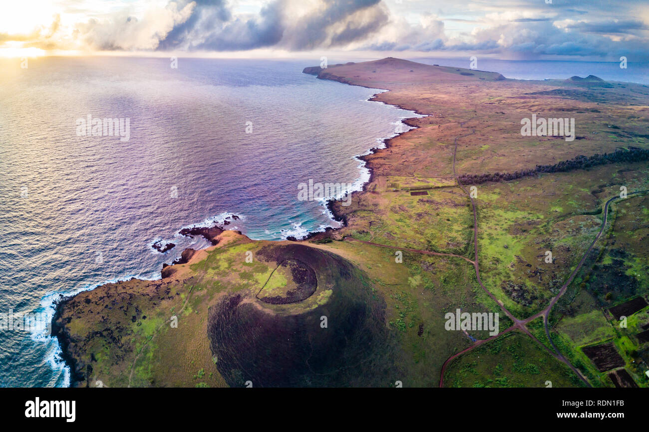 Aerial footage. Drone view at Easter Island cliffs during sunrise. An amazing view of the Pacific Ocean crashing the coastline and the sun rising Stock Photo
