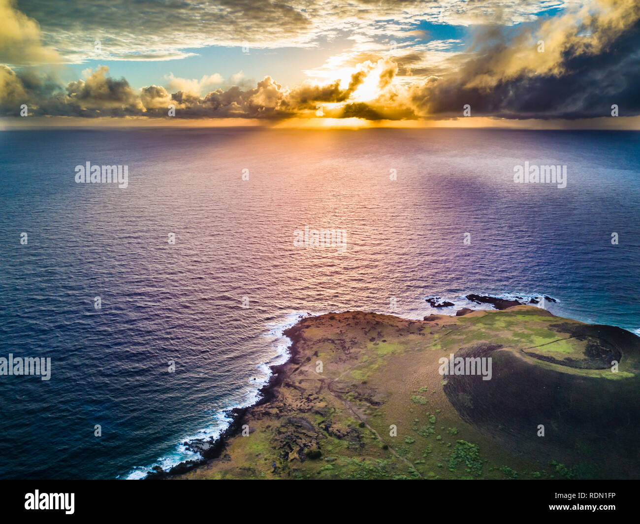 Aerial footage. Drone view at Easter Island cliffs during sunrise. An amazing view of the Pacific Ocean crashing the coastline and the sun rising Stock Photo