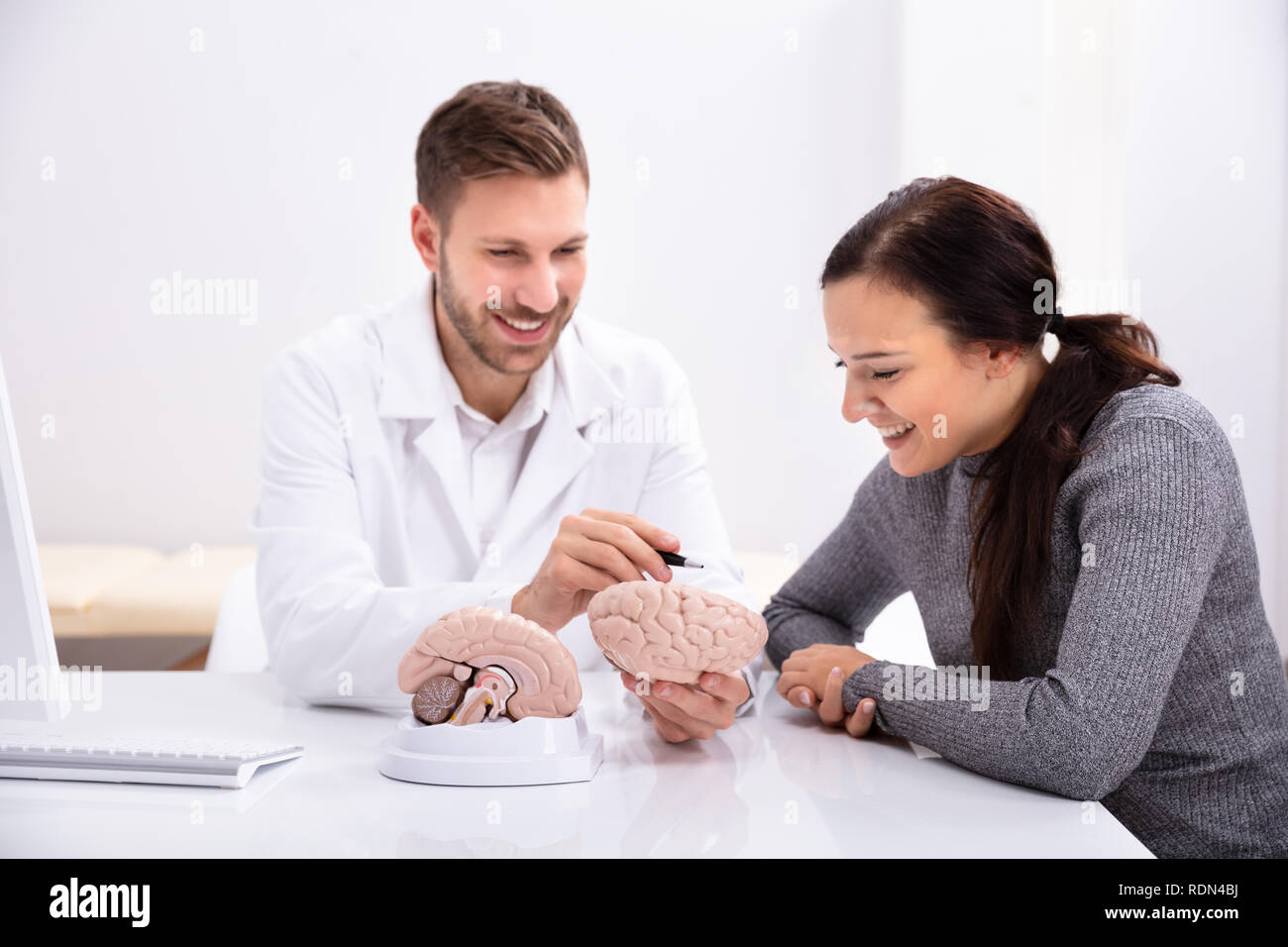 Doctor Explaining Details Of Human Brain To Happy Woman With Model Stock Photo