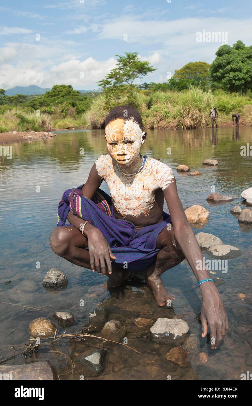Surma boy with facial and body painting in the river, Kibish, Omo River Valley, Ethiopia, Africa Stock Photo