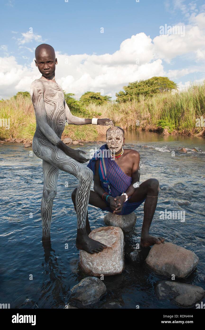 Two Surma men with facial and body paintings in the river, Kibish, Omo River Valley, Ethiopia, Africa Stock Photo
