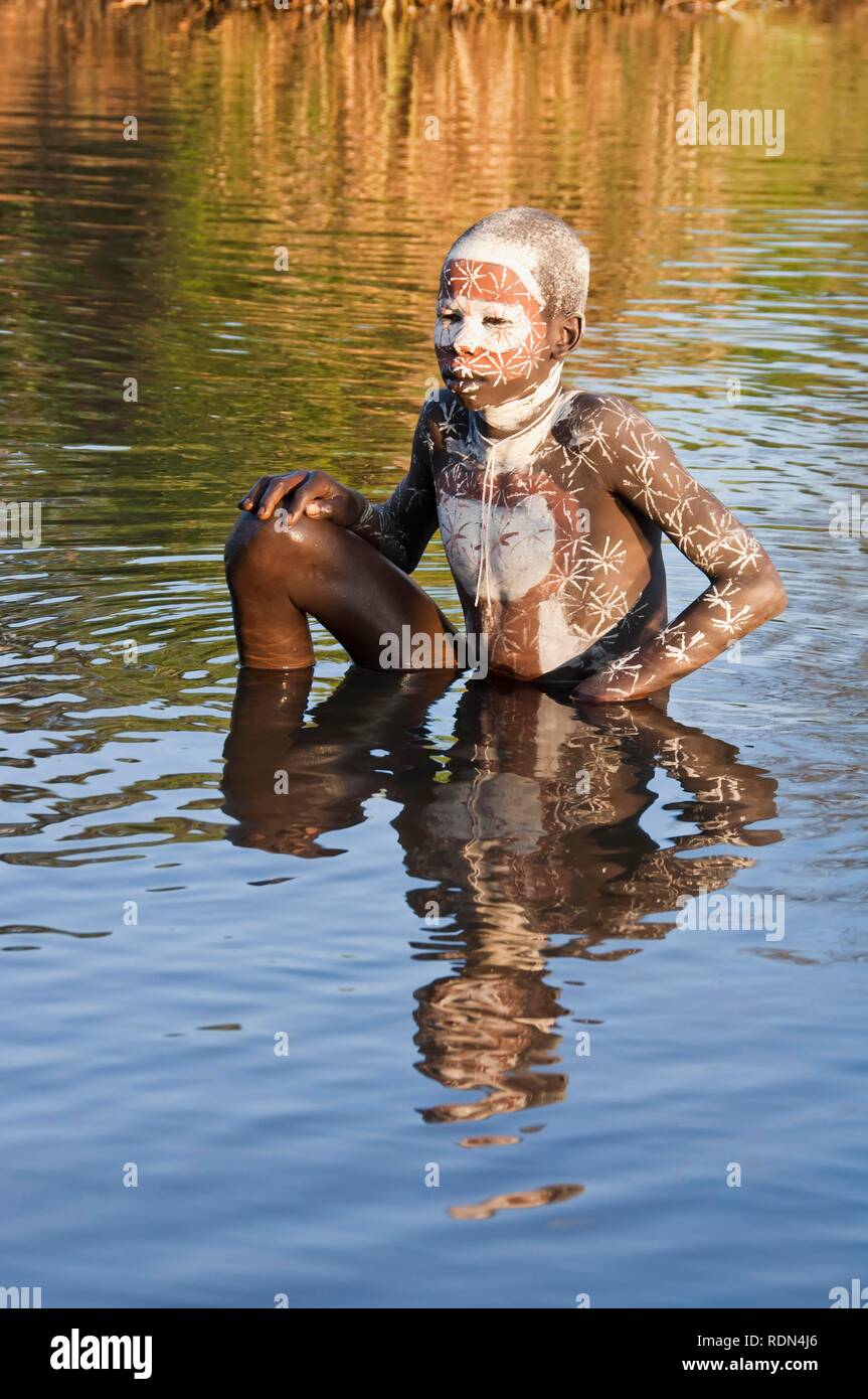 Surma boy with facial and body painting in the water, Kibish, Omo River Valley, Ethiopia, Africa Stock Photo