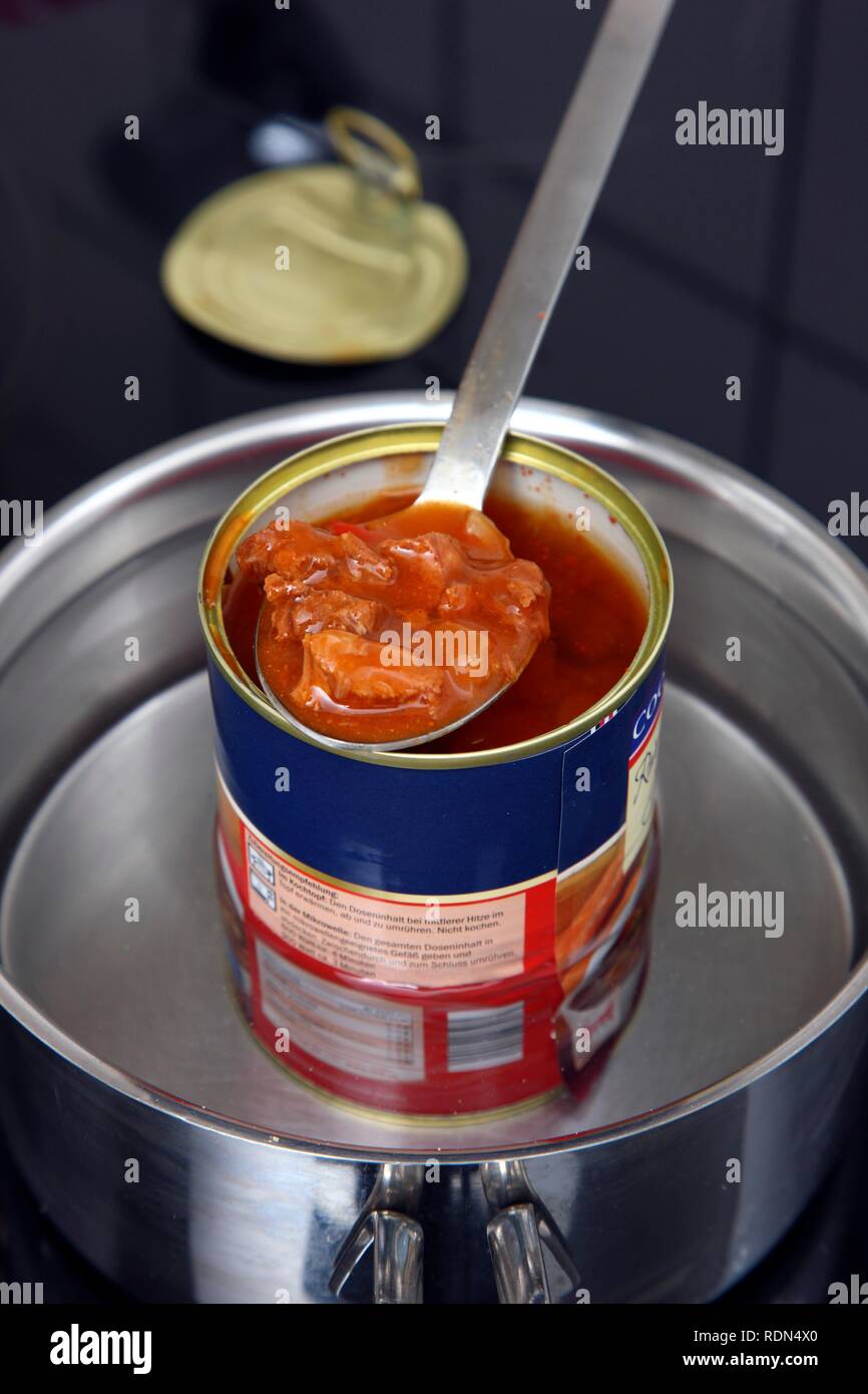 Reheating an instant meal in a tin can in a water bath, goulash soup Stock Photo