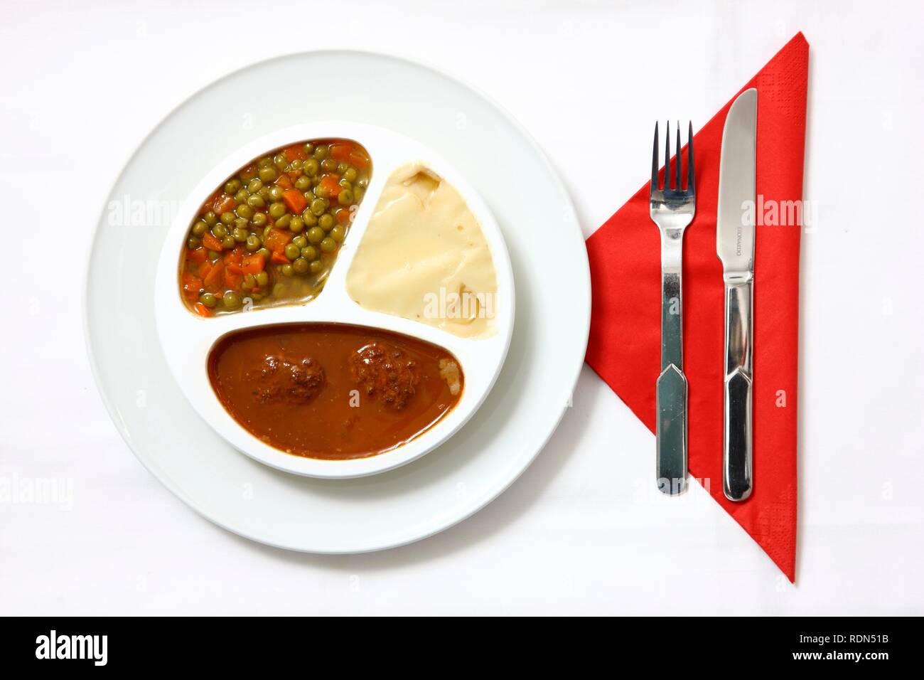 Meatballs with sauce, peas, carrots and mashed potatoes, pre-prepared meal, served on a plate, in the original packaging Stock Photo