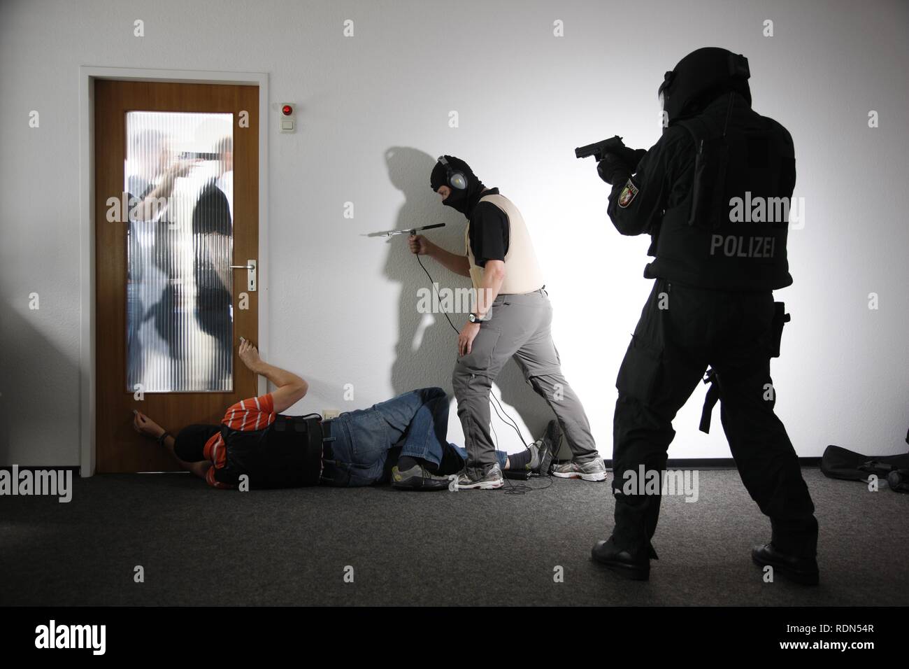 Members of a technical task force of the special police unit listening to a conversation behind a door where a hostage has been Stock Photo