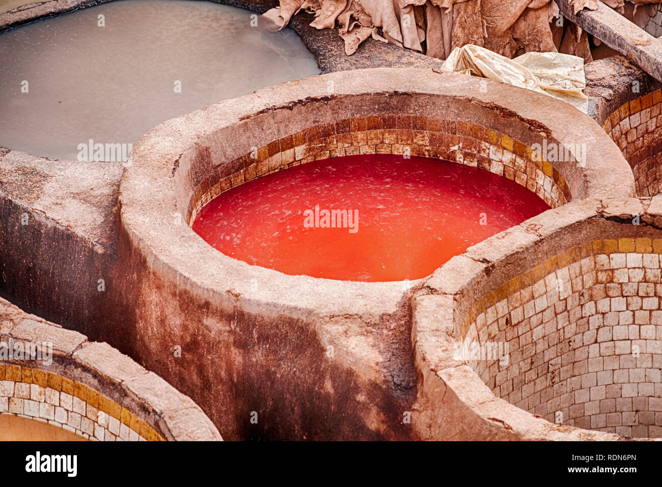 The outdoor leather tannery of Fes in Moroco contains hundreds of dye pits including some with bright red dyes. Stock Photo