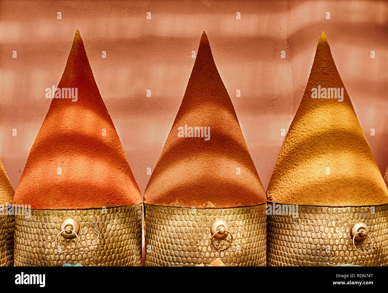 Spices are built into large cones for display in the spice markets in the Marrakesh souk in Morocco. Bands of light come from the ceiling covering. Stock Photo
