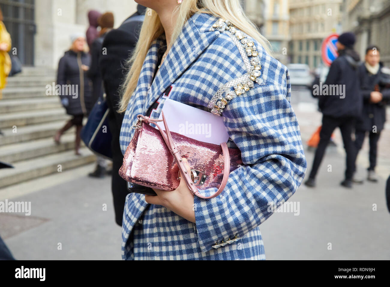 MILAN, ITALY - JANUARY 12, 2019: Woman with pink sequin bag and blue and white checkered jacket before Frankie Morello fashion show, Milan Fashion Wee Stock Photo