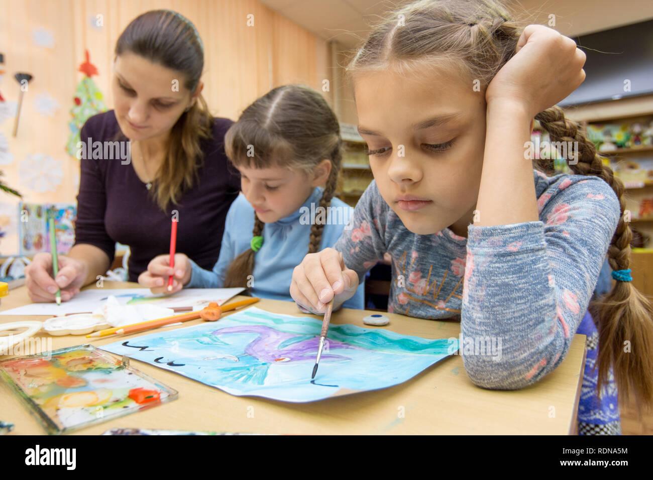 The teacher helps the students in drawing class Stock Photo