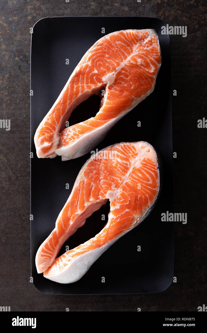 Fresh salmon fish steaks on black background top view Stock Photo - Alamy