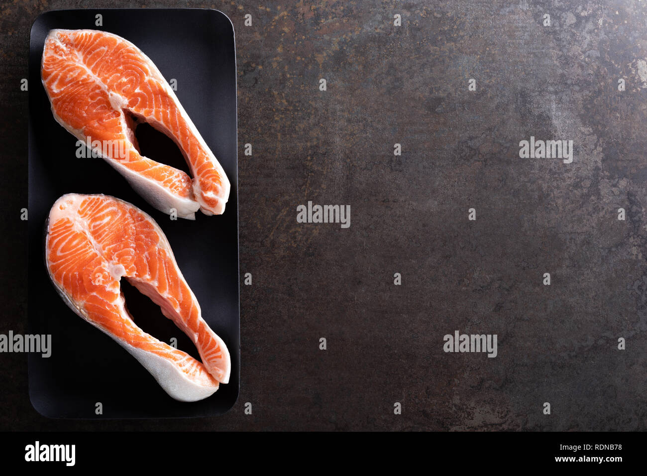 Fresh salmon fish steaks on black background top view Stock Photo - Alamy
