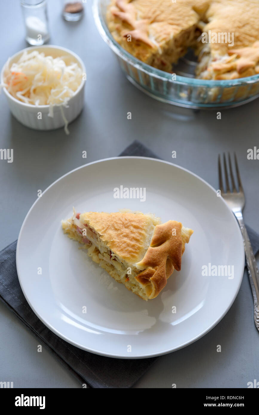 Slice of homemade sauerkraut pie on gray wooden table. Cabbage cake