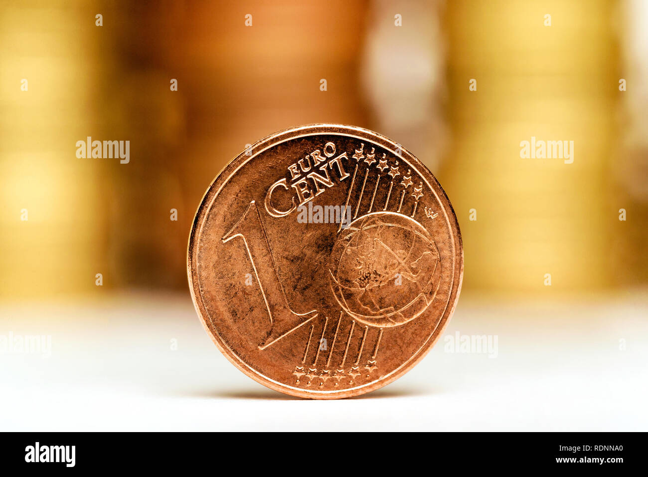Close up of One Euro Cent and piles of coins on a white background Stock Photo