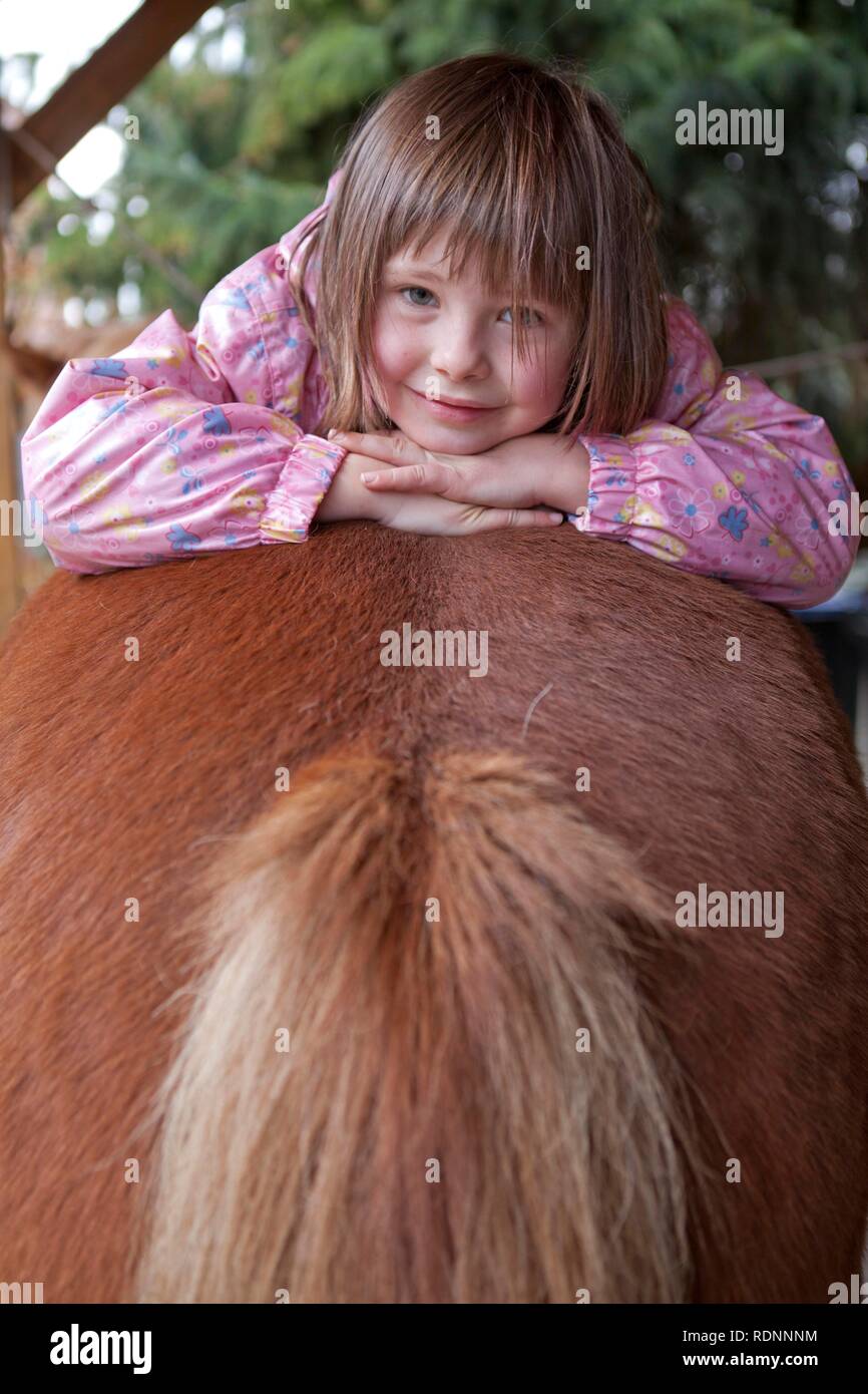 Young girl lying on a pony Stock Photo