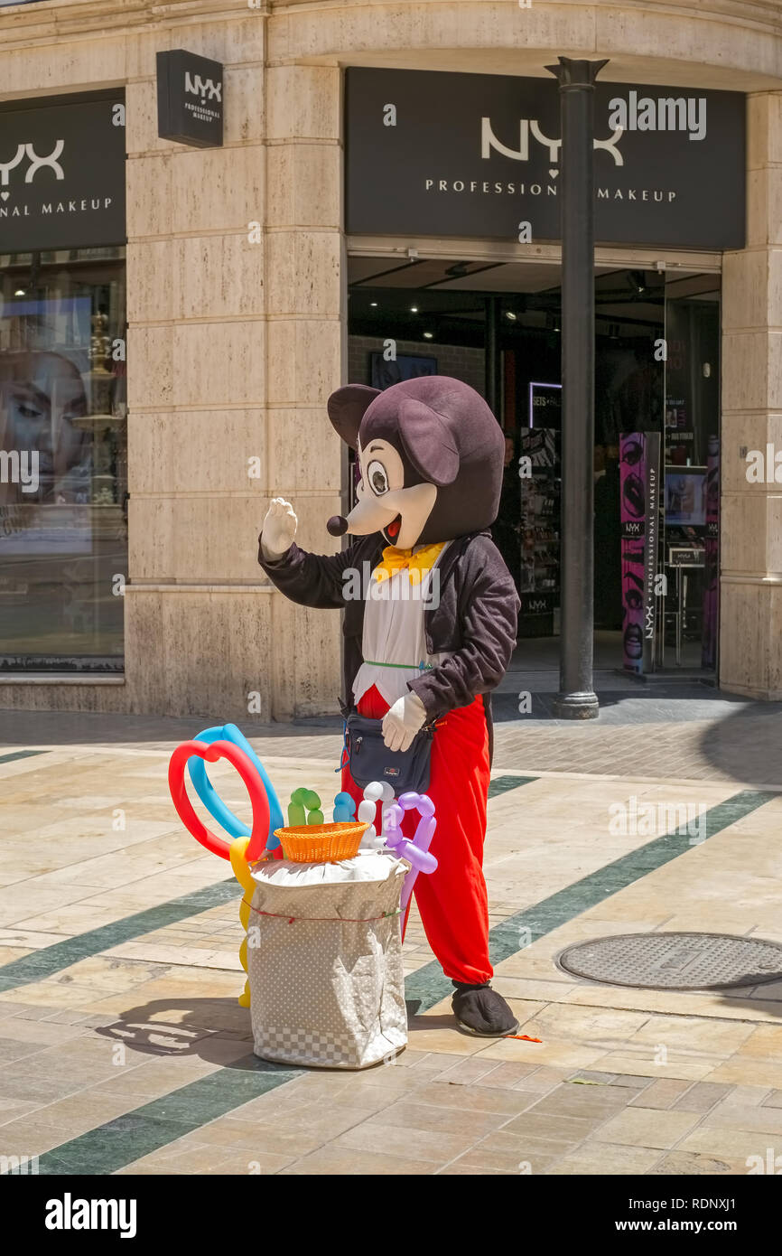 Malaga, Spain - May 26, 2018. Disney Mickey Mouse costumed character selling balloons to children at Constitution square, Malaga city, Costa del Sol,  Stock Photo