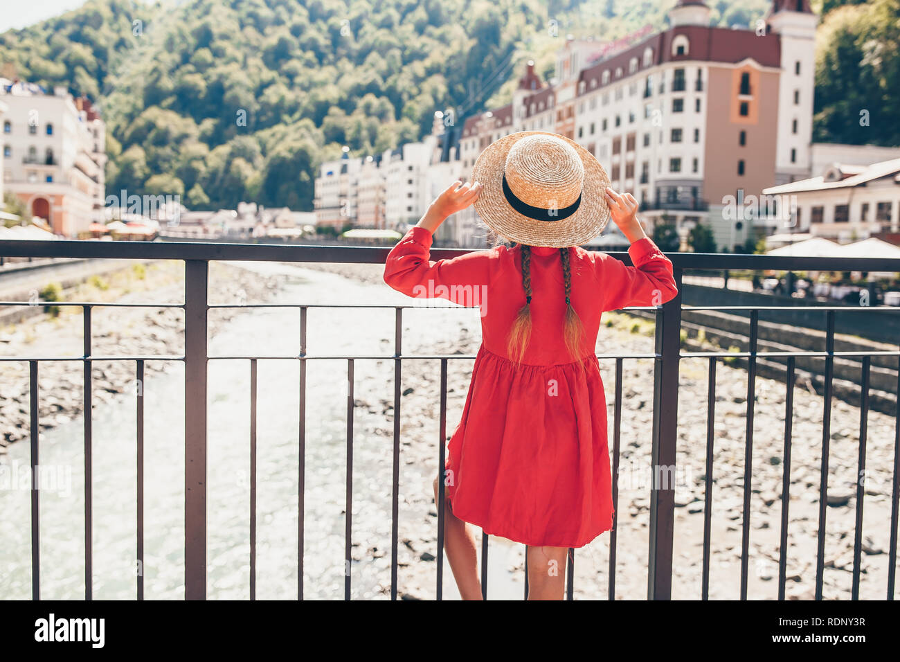 Little girl at hat on the embankment of a mountain river in a European ...