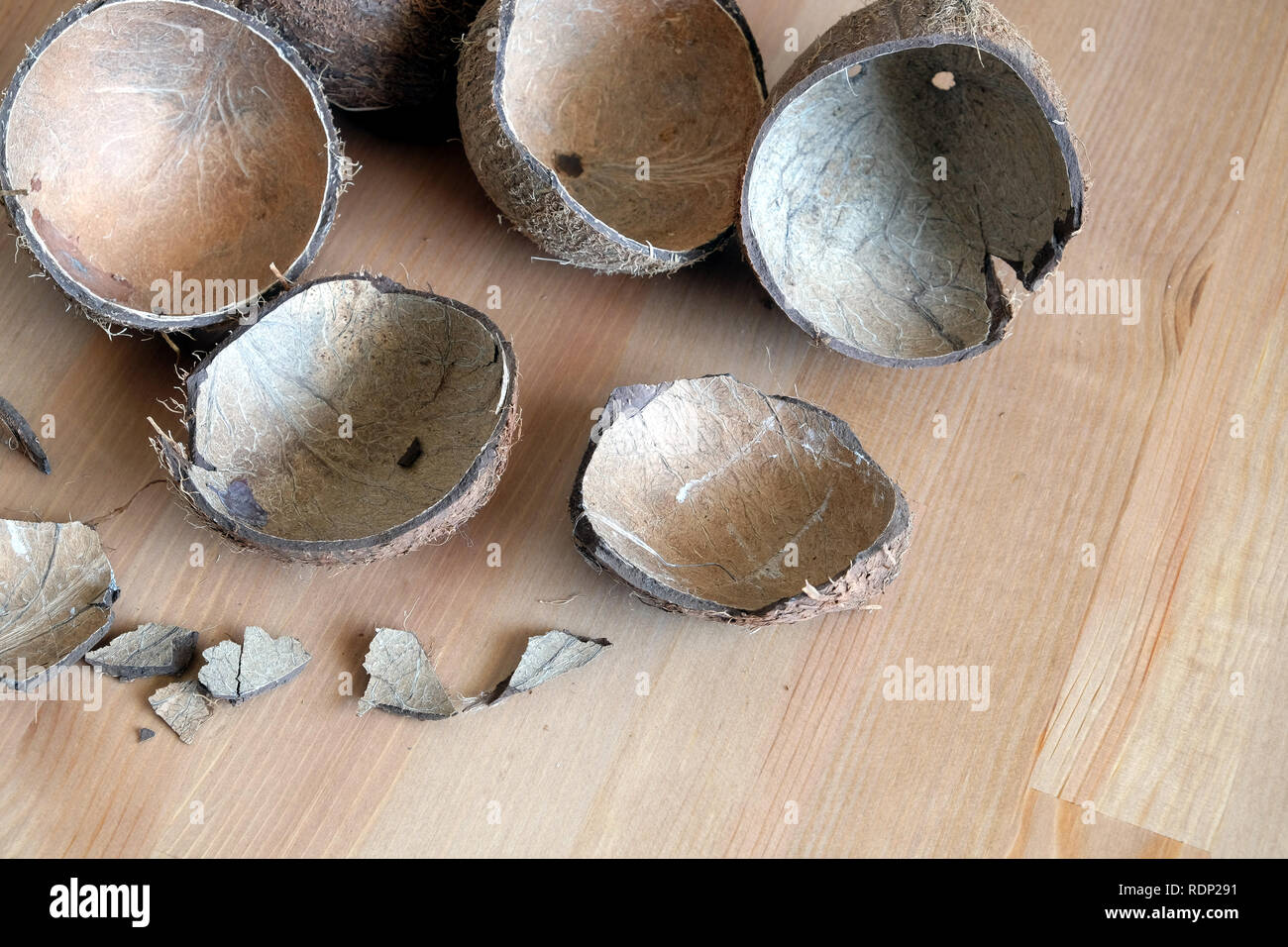 Still life with broken coconut shell ripe white flesh inside and debris on brown wooden table as background. Horizontal close up photo Stock Photo