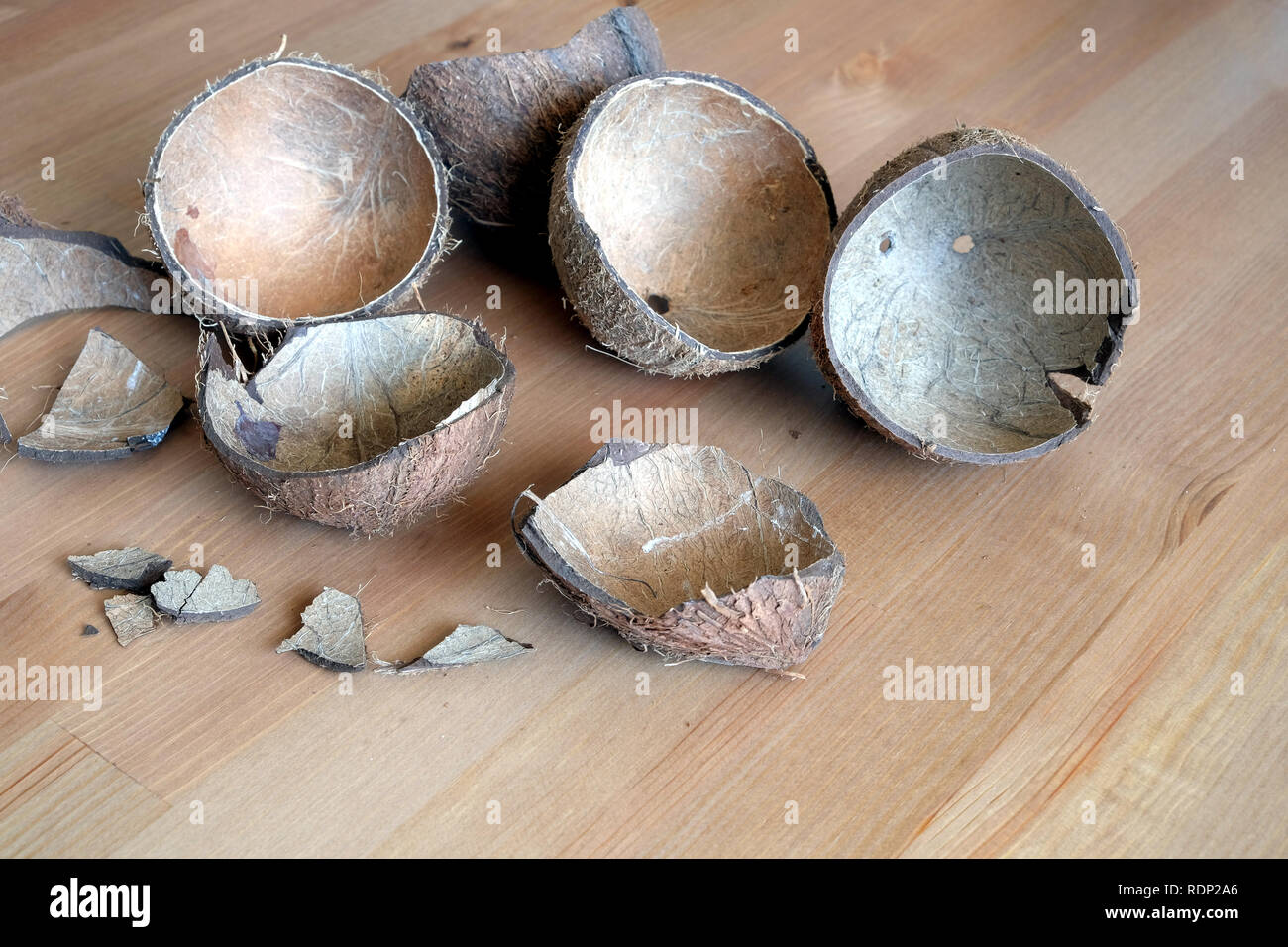 Still life with broken coconut shell ripe white flesh inside and debris on brown wooden table as background. Horizontal close up photo Stock Photo