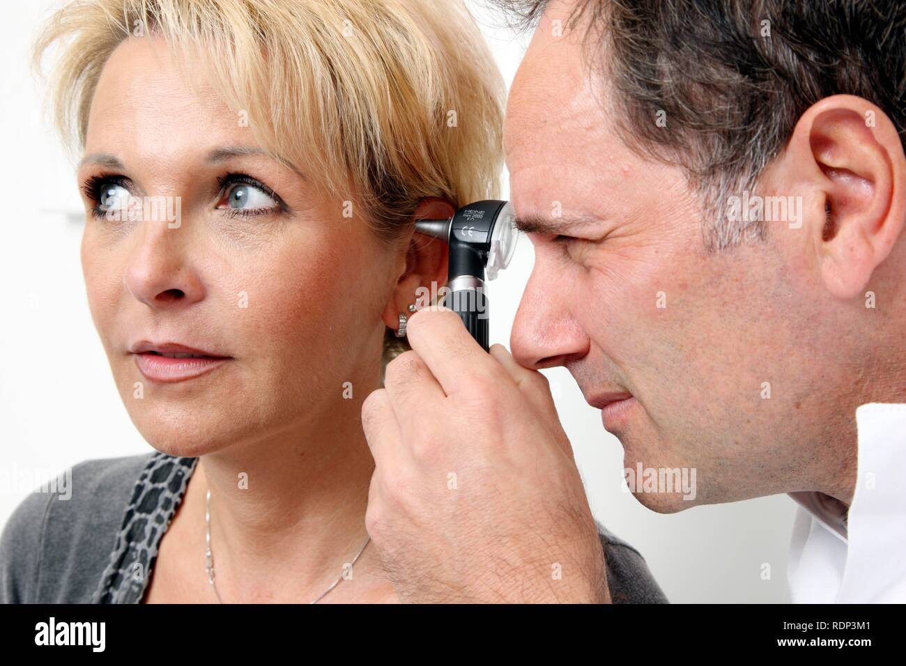 Doctor's surgery, doctor examining a patient's ear canal using an ear speculum Stock Photo