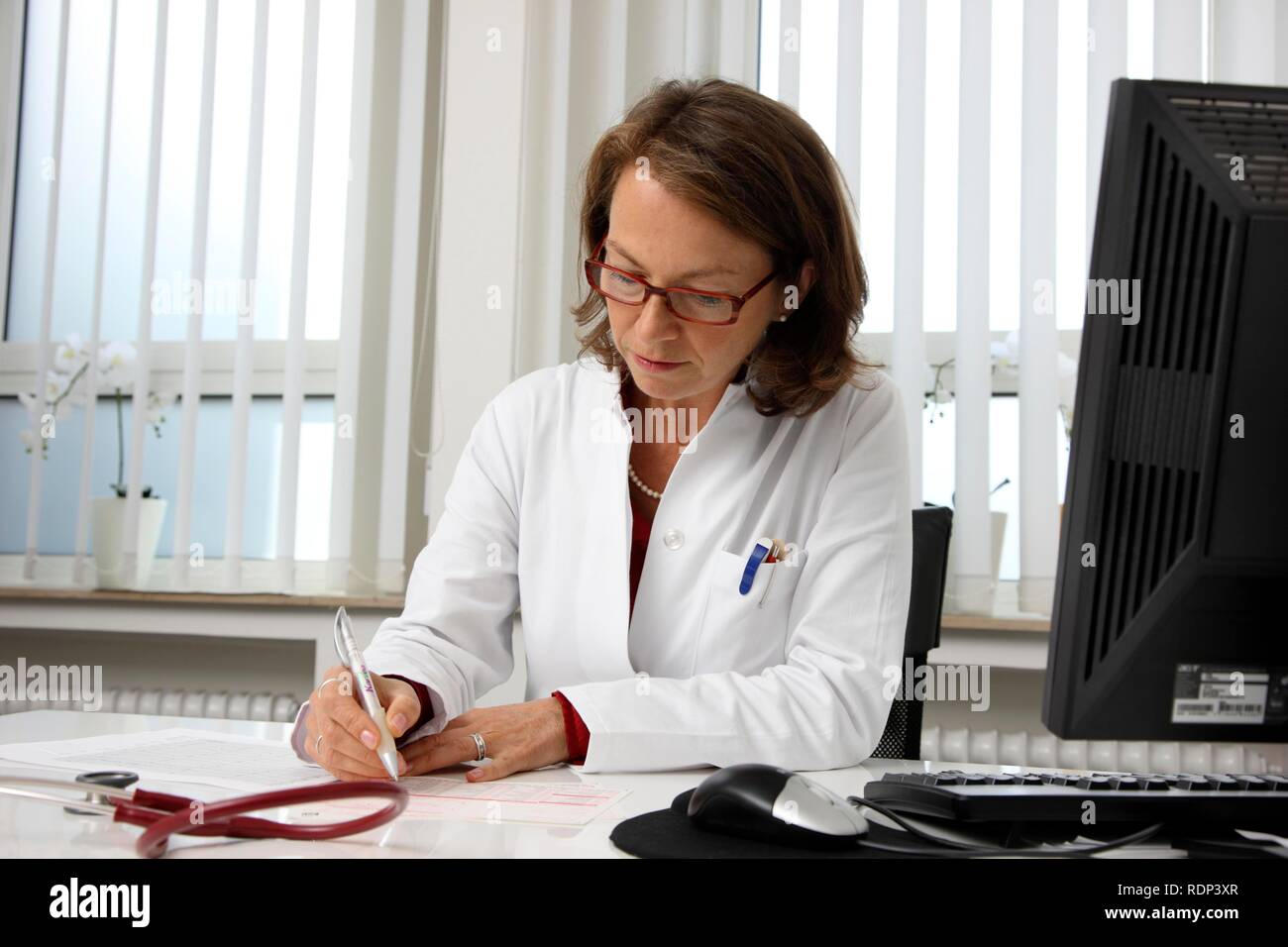 Medical practice, doctor examining the health records of a patient at her desk Stock Photo