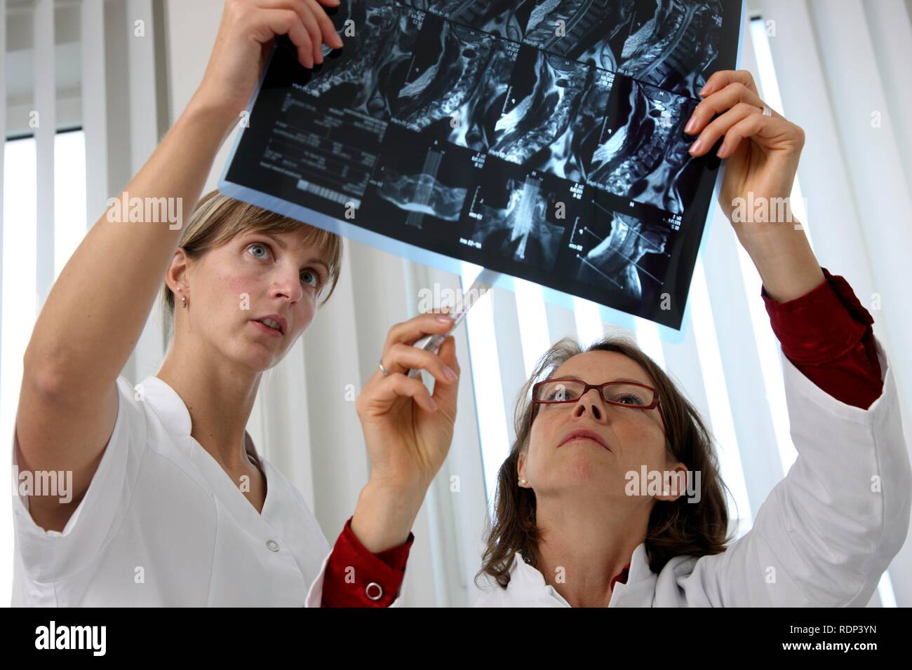 Medical practice, doctor and medical technician examining MRT images ...