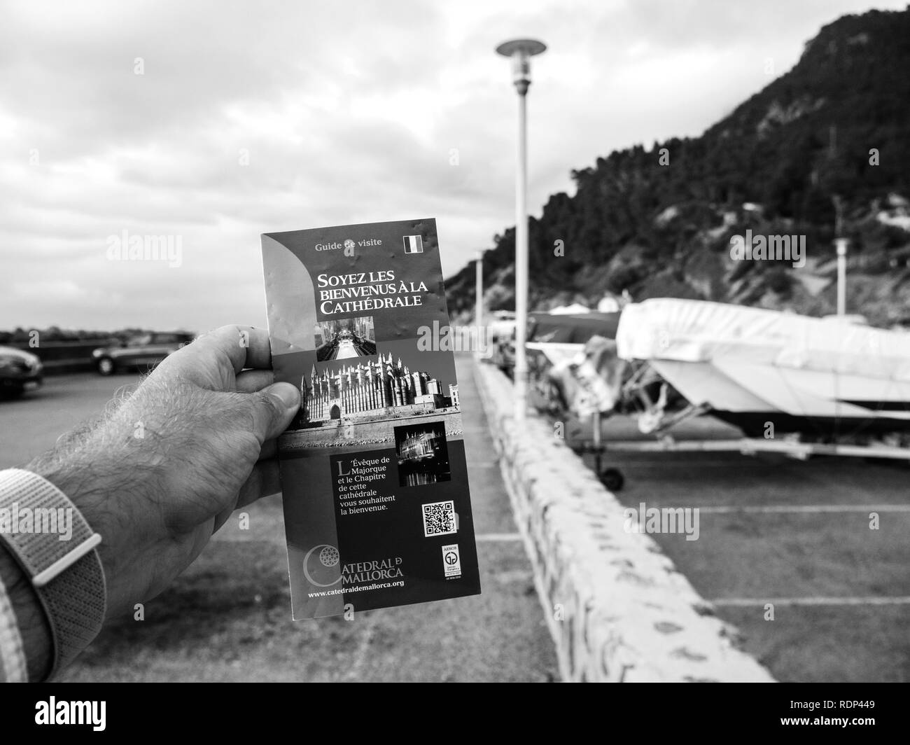 Port de Valldemosa, Palma de Malloca, Spain - May 10, 2018: Man holding pov the touristic guide of the Santa Maria of Palma Cathedral in the parking of Port de Valldemosa - black and white Stock Photo