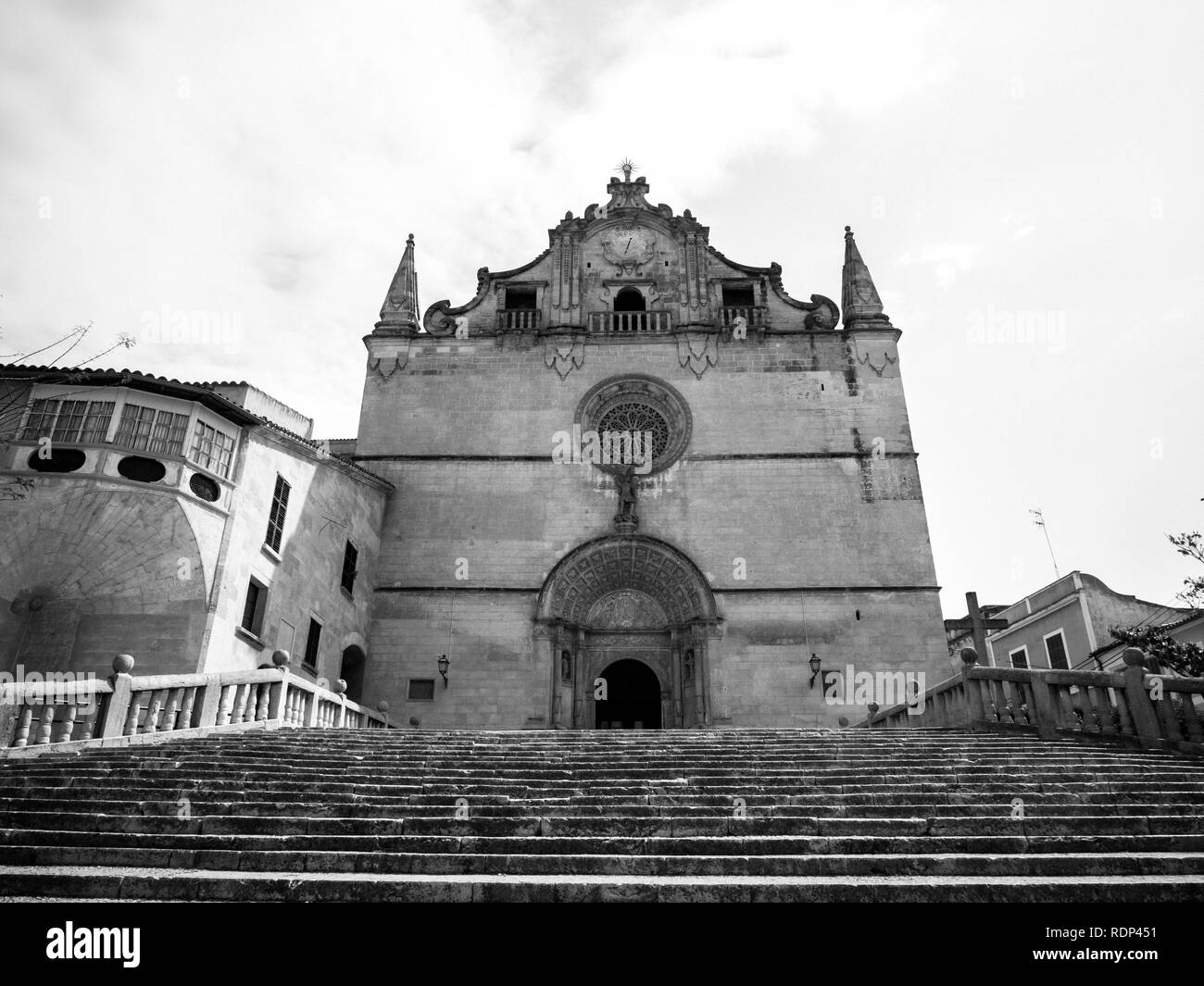 Sant Miquel church facade in central town of Felanitx on a sunny warm day with iconic stairs and large yellow stone facade - black and white Stock Photo