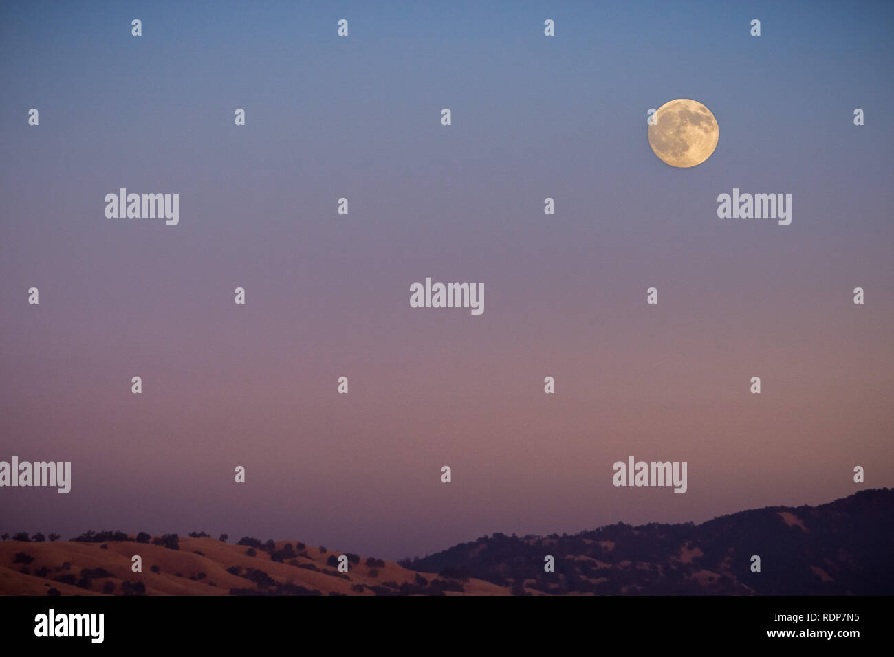 Full moon rising over a mountain ridge, California Stock Photo