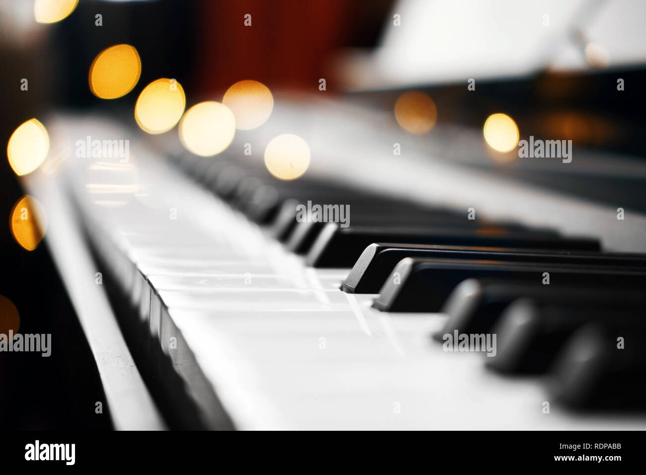 piano keys with beautiful yellow lights bokeh in background, piano keys