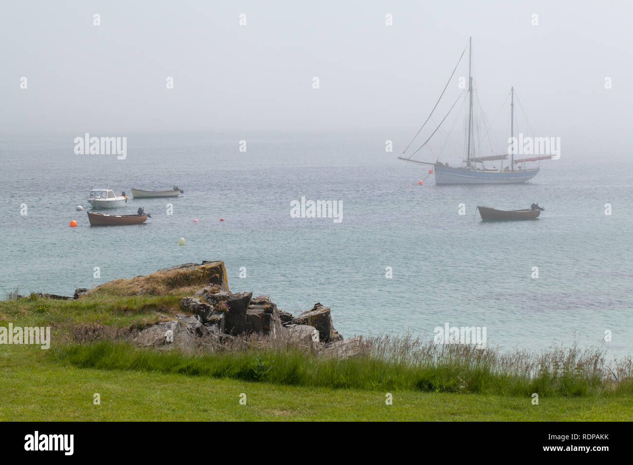 Anchored Boats.  View from The Village, St. Ronan’s Bay, Isle of Iona, across The Sound, towards Fionnphort, Mull, horizon obscured by early morning's sea mist.The Inner Hebrides. Scotland, Stock Photo