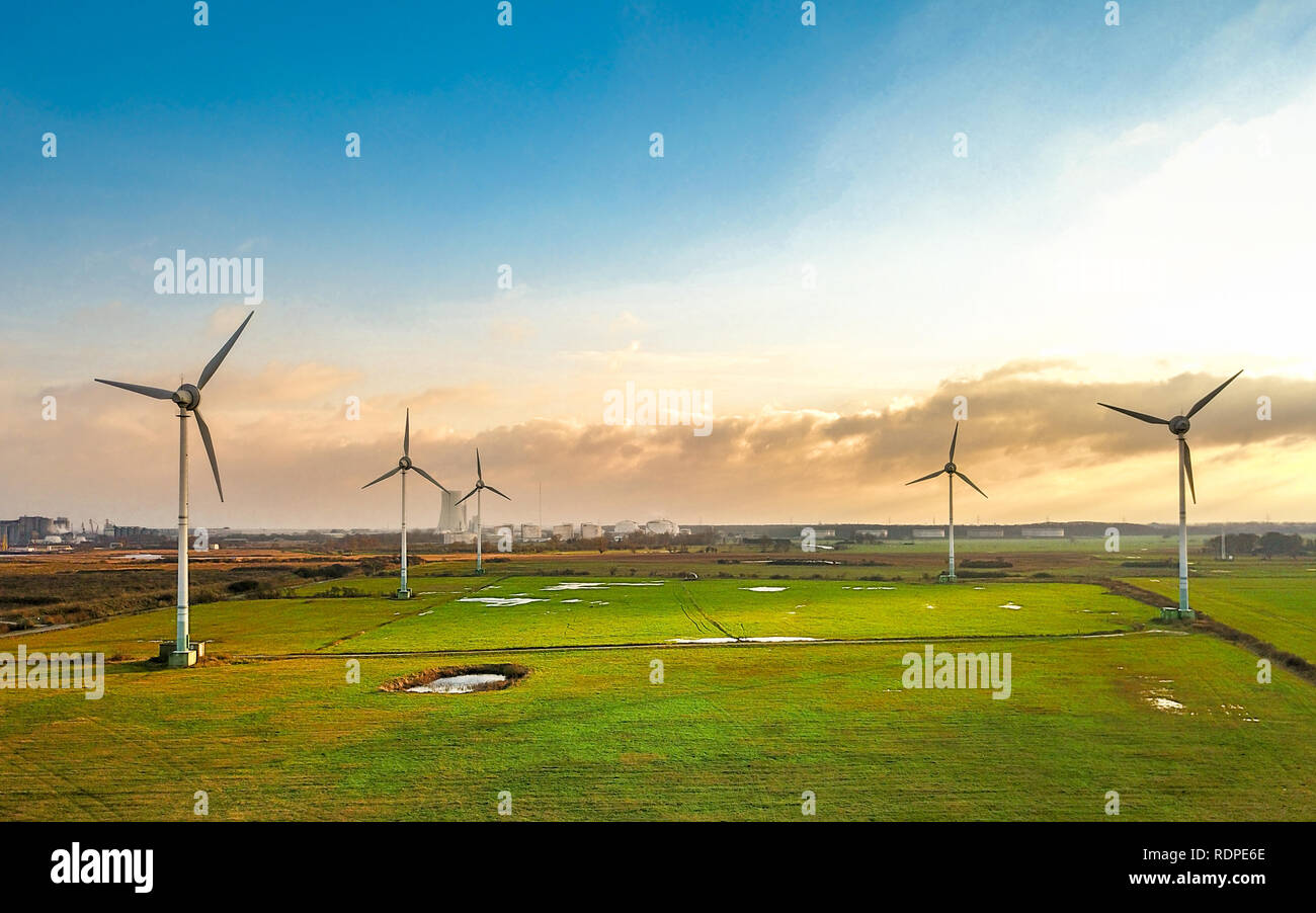 aerial view over a meadow with windmill or wind generator - renewable energy harvesting Stock Photo