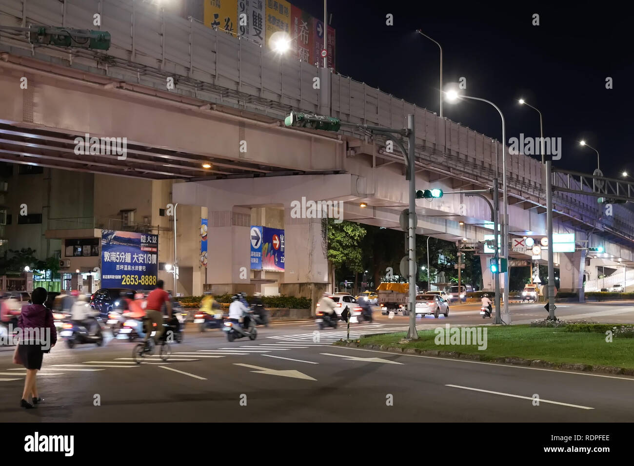 Taipei, Taiwan - November 30, 2018 : Motion of commuters and cars passing by road at night Stock Photo