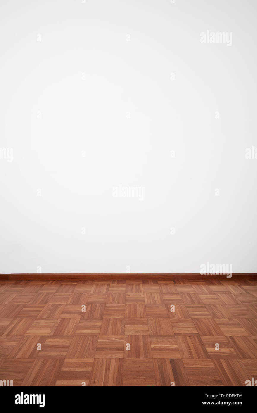 Empty room with dark wooden tiled floor and white blank wall Stock Photo