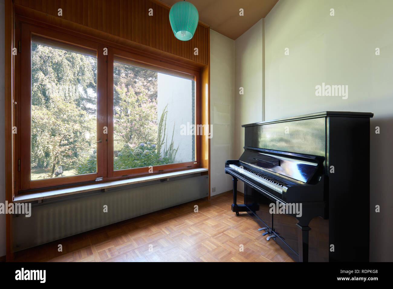 Room with piano and large window, apartment interior in old house with garden Stock Photo