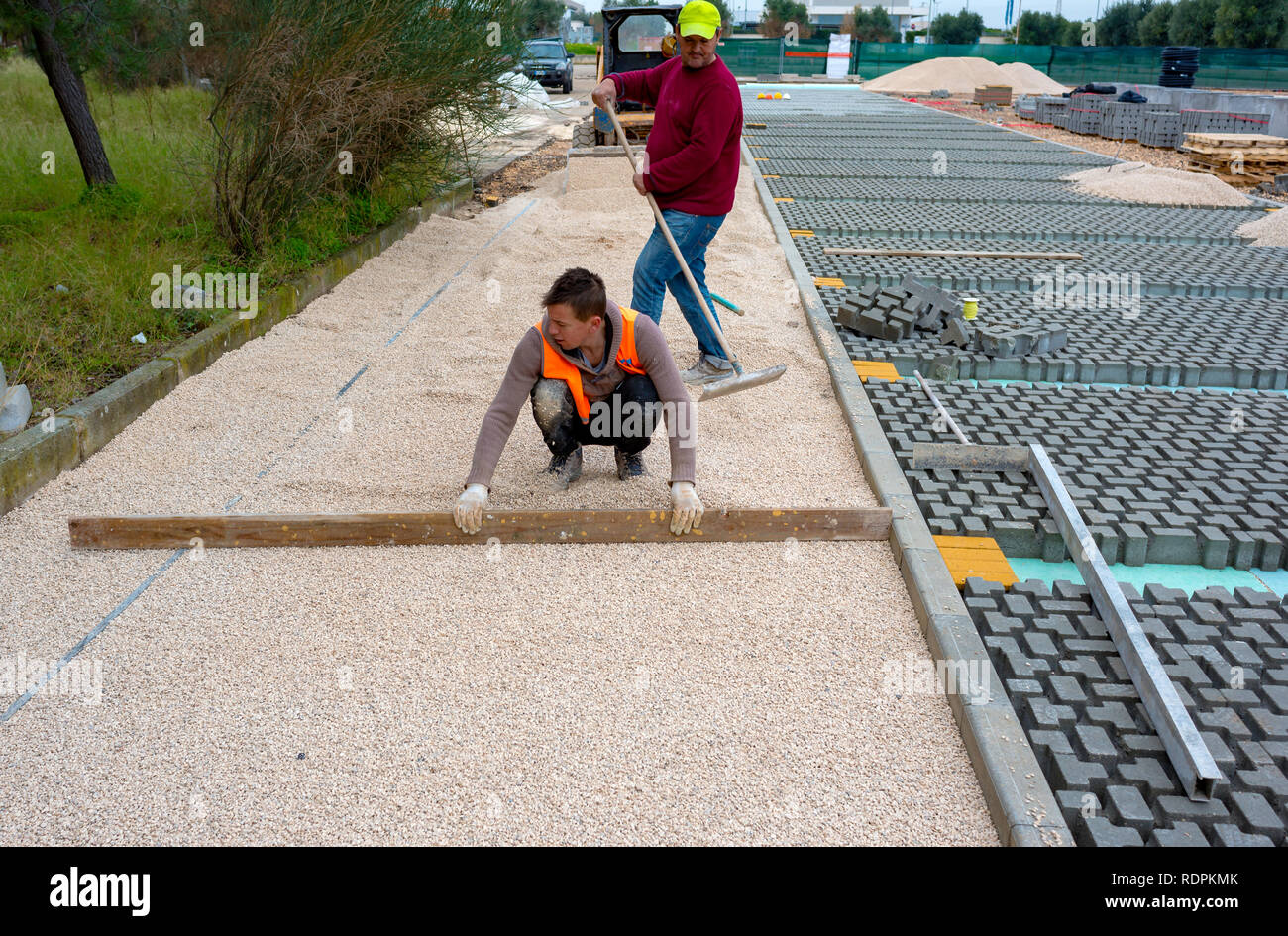 Construction worker laying interlocking paving concrete onto sheet