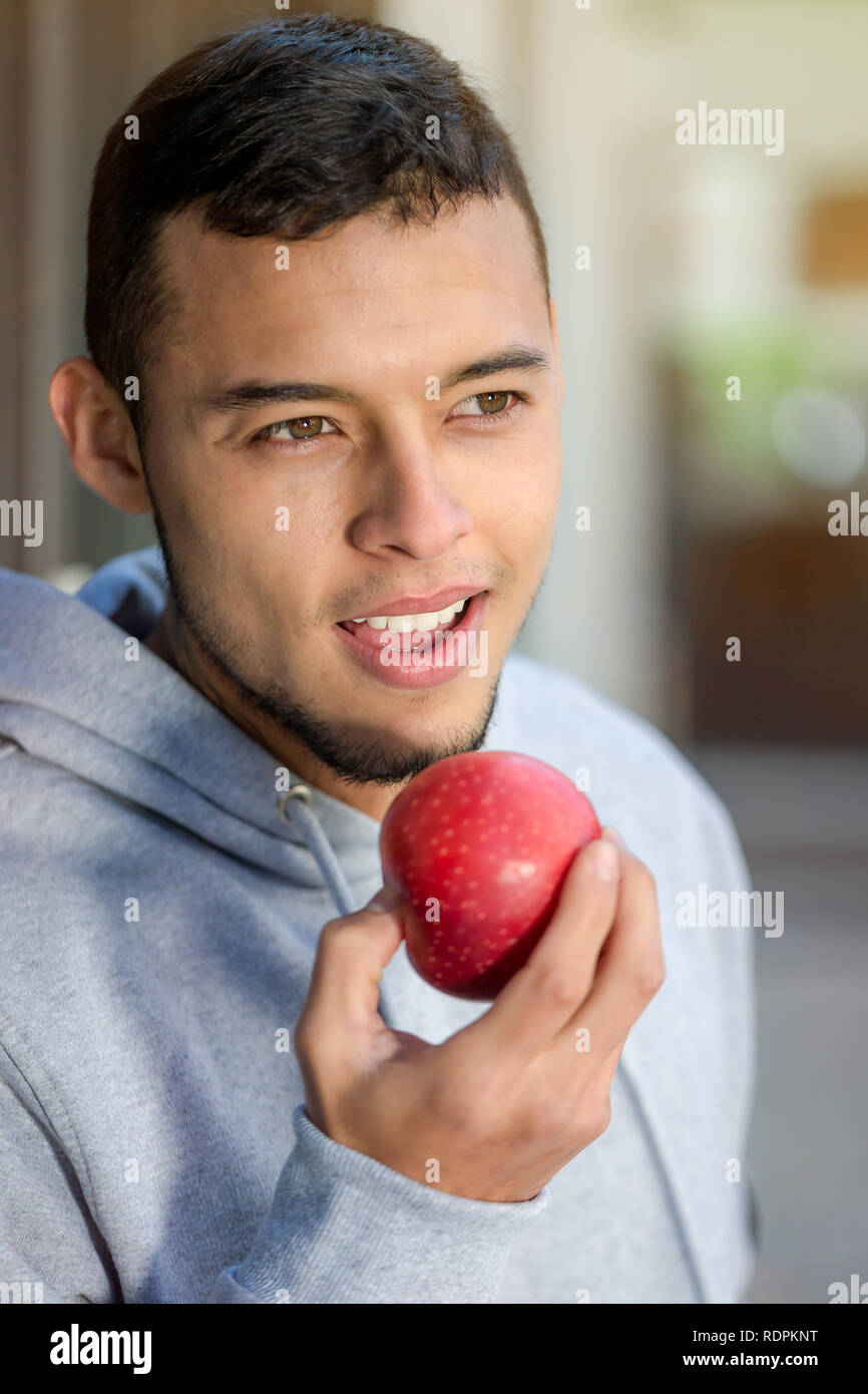 Young latin man eating apple fruit runner winter portrait format running sports training fitness outdoor Stock Photo