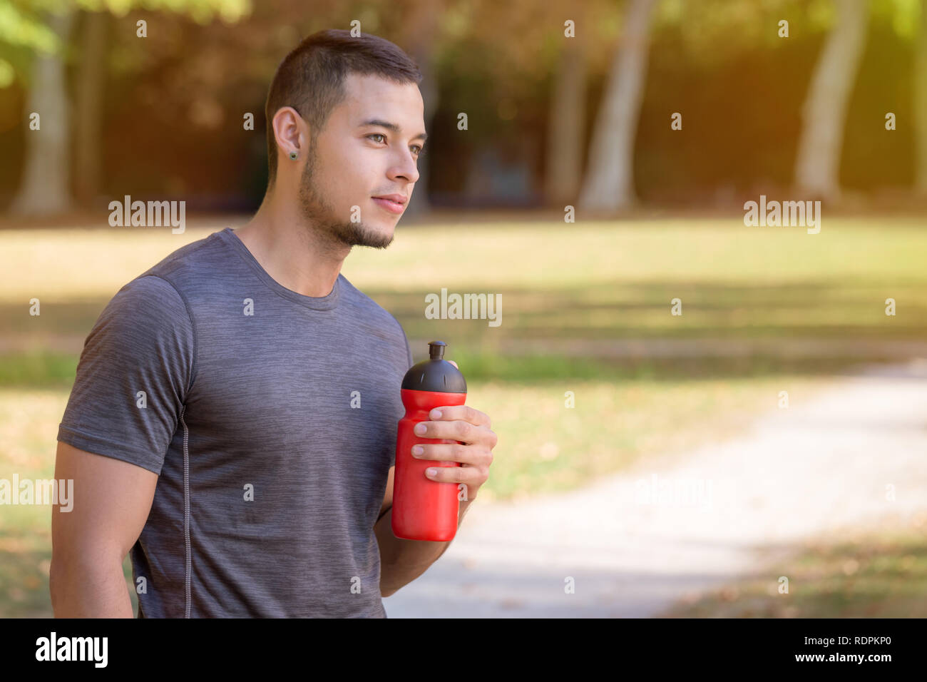 Latin man runner looking thinking water bottle running jogging sports training fitness copyspace copy space outdoor Stock Photo