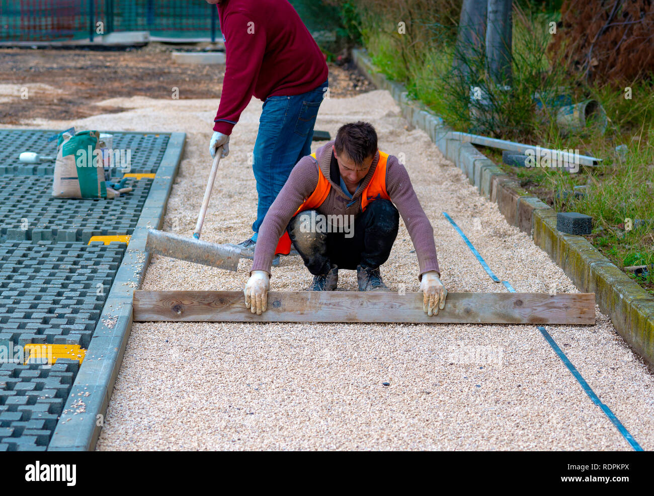 Construction worker laying interlocking paving concrete onto sheet
