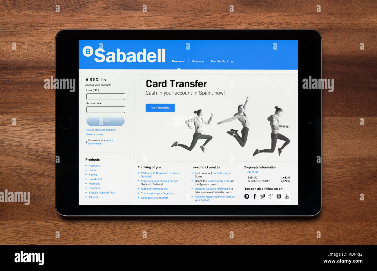 The website of Banco Sabadell is seen on an iPad tablet, which is resting on a wooden table (Editorial use only). Stock Photo